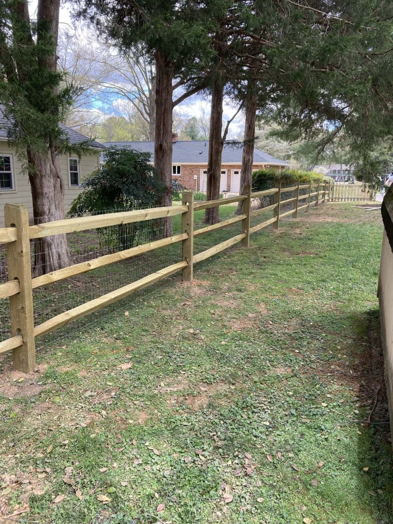 wooden agricultural fence with trees behind it