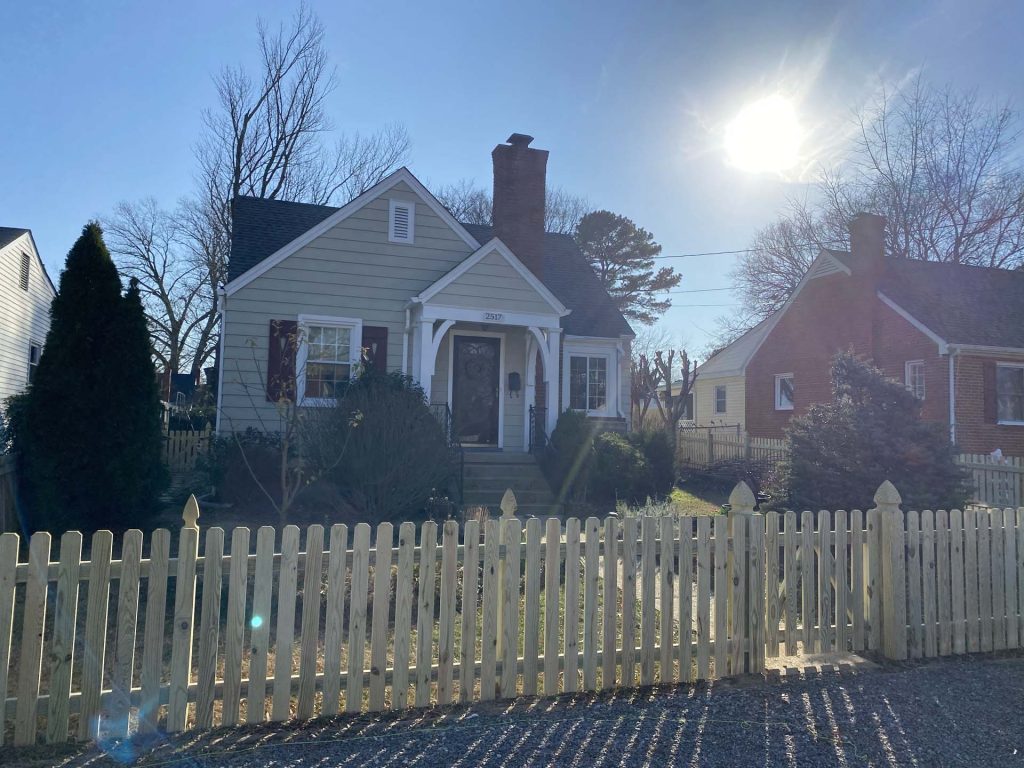 wooden picket fence surrounding a classic style home